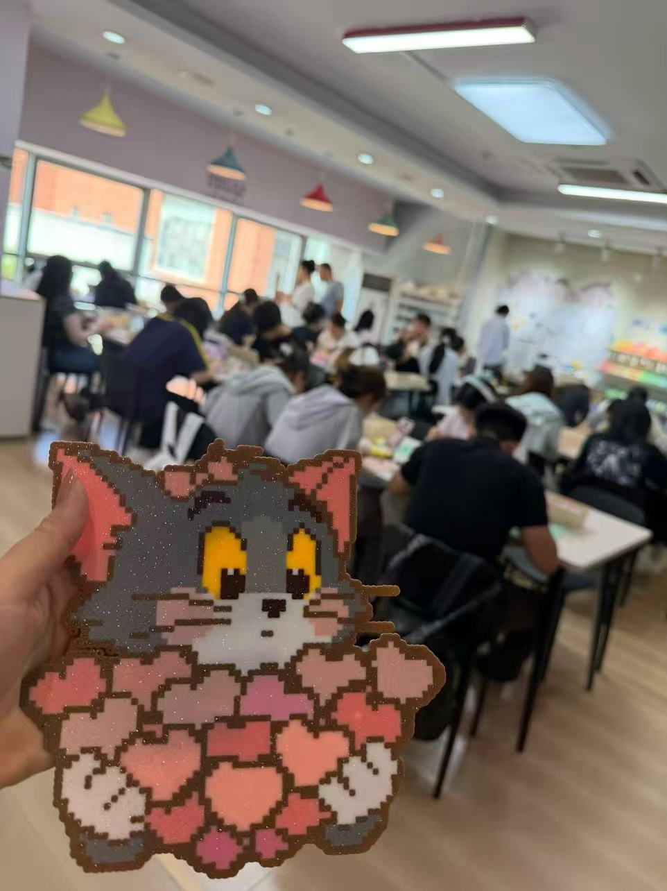 顾客展示拼豆猫咪成品，背景为高客流门店